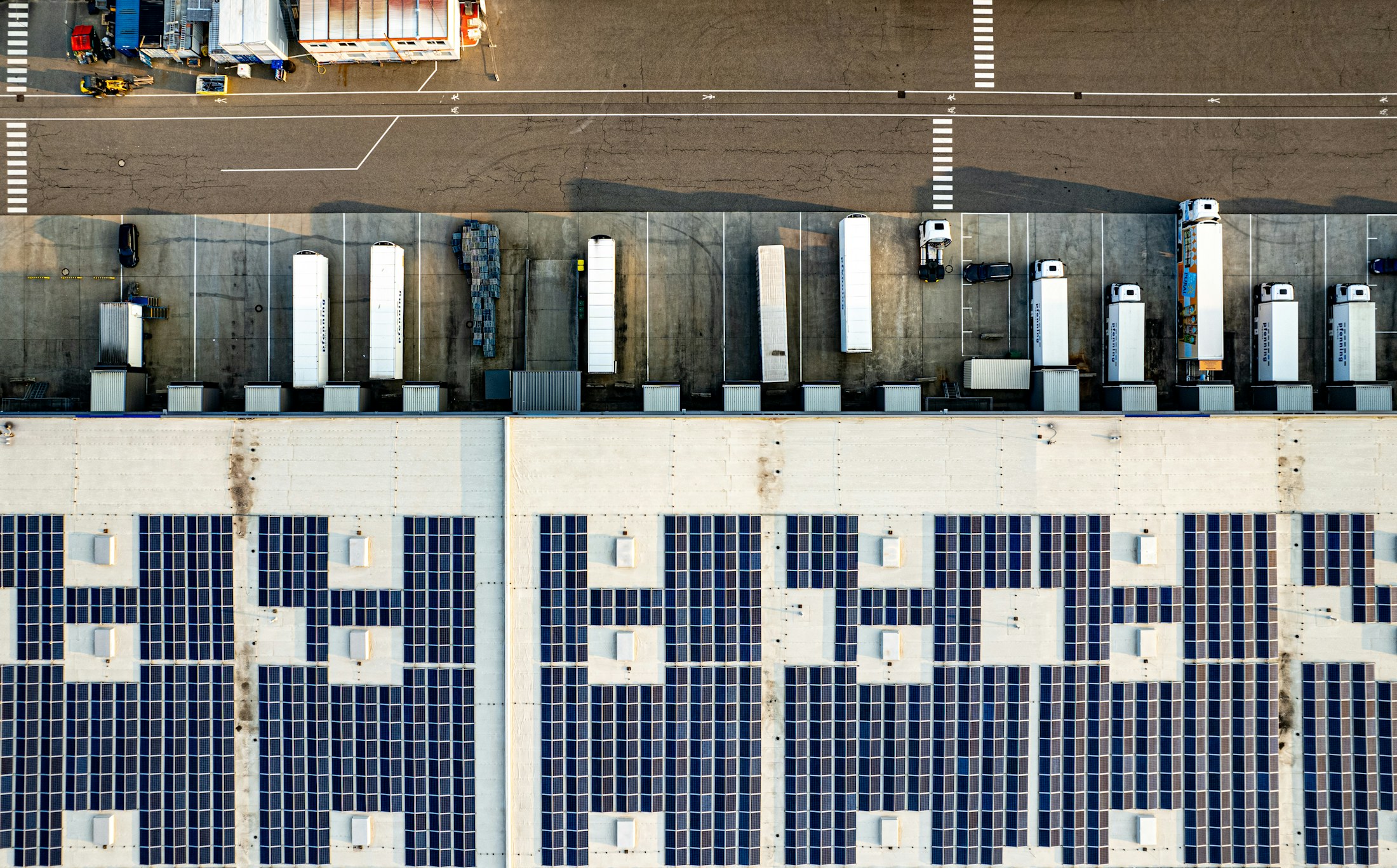 Aerial view of a logistics facility with rooftop solar panels and freight vehicles